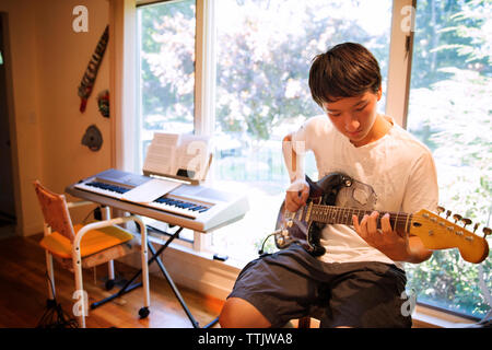 Adolescente praticando una chitarra elettrica a casa Foto Stock