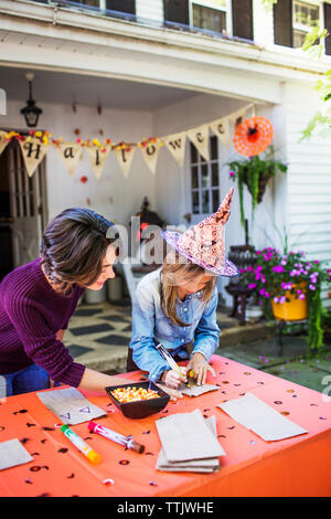 Madre figlia che assiste nella realizzazione di decorazione a tavola durante la festa di Halloween Foto Stock