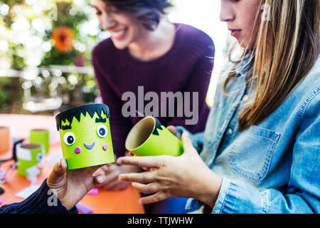 Felice madre rendendo decorazione con i bambini a tavola durante la festa di Halloween Foto Stock