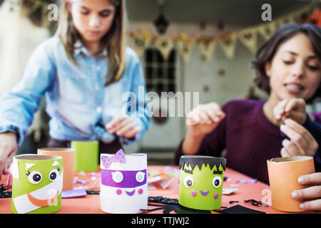 Madre facendo varie decorazione con i bambini a tavola durante la festa di Halloween Foto Stock