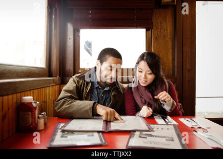 Giovane guardando il menu durante la seduta in ristorante Foto Stock