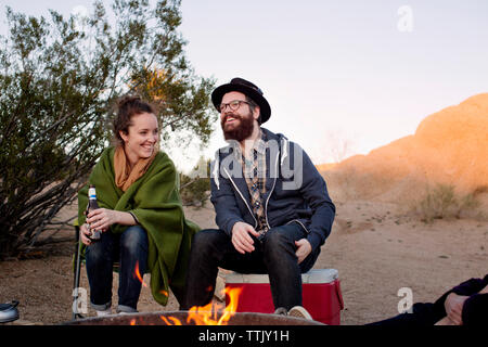 Giovane seduto a parlare durante la seduta da una buca per il fuoco Foto Stock
