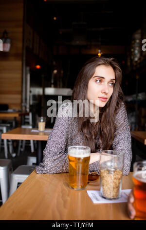 Premurosa donna con birra seduti a tavola in fabbrica di birra Foto Stock