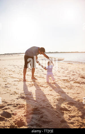 Padre e figlio giocando sulla riva del mare in spiaggia contro il cielo chiaro Foto Stock