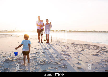 Per tutta la lunghezza della famiglia permanente sulla spiaggia contro sky sulla giornata di sole Foto Stock