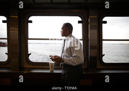 uomo d'affari che usa il telefono mentre prende un caffè al traghetto Foto Stock