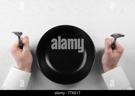 Uomo con cucchiaio e forchetta con piastra vuota. Concetto della fame Foto Stock