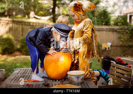 Fratelli carving zucca sul tavolo al cantiere durante il periodo di Halloween Foto Stock