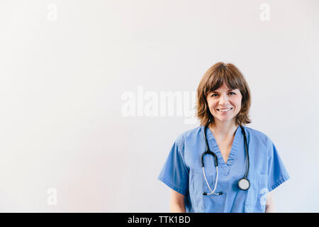 Ritratto di donna sorridente medico con stetoscopio in piedi contro uno sfondo bianco Foto Stock