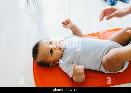 Ritagliate la mano della Madre di raggiungere verso il figlio giacente sulla coperta del bambino a casa Foto Stock