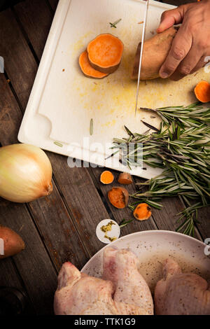 Immagine ritagliata dell'uomo carota di taglio sul tavolo di legno Foto Stock