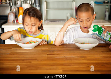 I fratelli con la colazione a tavola di legno in cucina Foto Stock