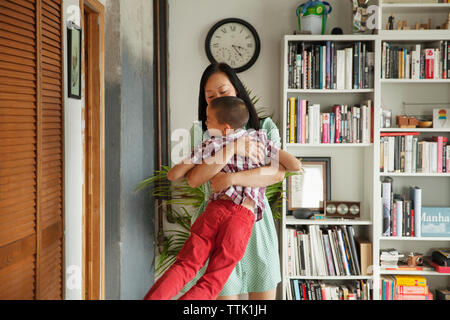 Giocoso madre abbracciando il figlio a casa Foto Stock