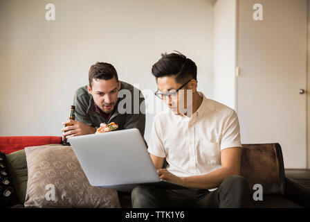 uomo d'affari che mostra il portatile al collega che porta pizza e birra in ufficio Foto Stock