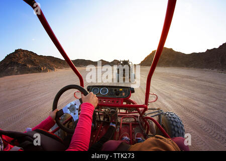 Immagine ritagliata di turisti spiaggia equitazione buggy su dessert contro il cielo chiaro Foto Stock