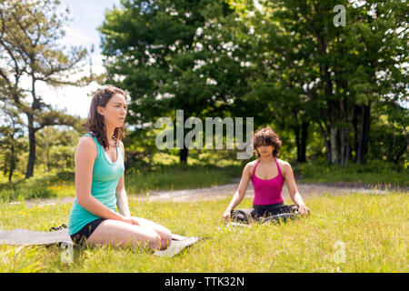 Donna che guarda lontano mentre amico esercita sul campo Foto Stock