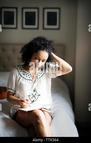 Donna con le mani nei capelli la scrittura sul libro Foto Stock