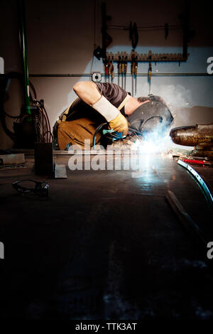 Lavoratore di sesso maschile la saldatura in fabbrica Foto Stock