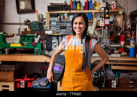 Ritratto di felice meccanico femmina indossando il grembiule in officina Foto Stock