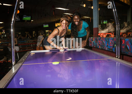 Gli amici sorseggiando air hockey club Foto Stock