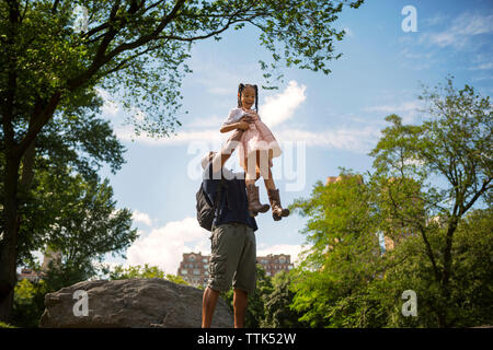 Basso angolo di visione del padre che porta la figlia contro sky Foto Stock