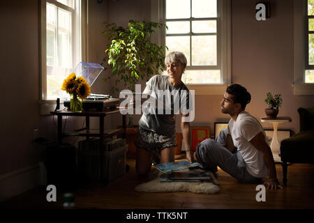 Uomo che guarda la donna holding vinile sul pavimento a casa Foto Stock