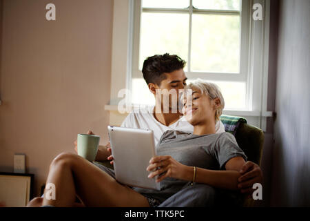 Uomo Donna baciare utilizzando tablet pc a casa Foto Stock