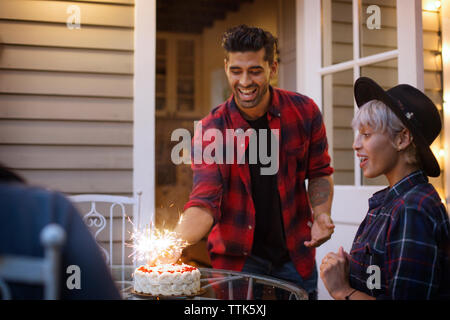 L'uomo posizionando la torta sul tavolo per sorpreso donna Foto Stock