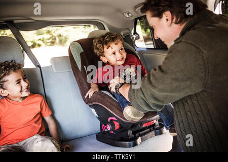 Padre immissione figlio sul seggiolino per bambino in automobile Foto Stock