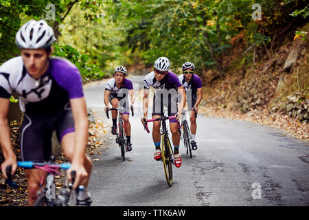 Fiducioso atleti maschio equitazione biciclette su strada Foto Stock