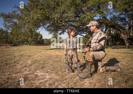 Padre e figlia holding tiro con l'arco archi sul campo erboso Foto Stock