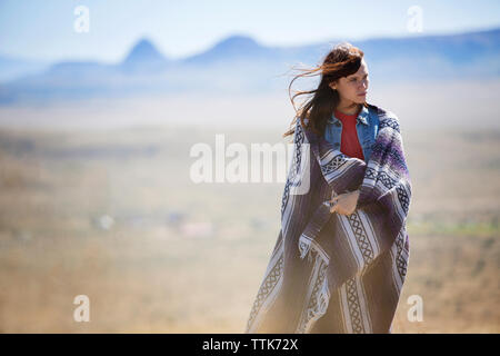 Premurosa donna avvolta in una coperta a piedi sul campo Foto Stock