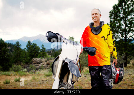 Ritratto di uomo in piedi da dirt bike contro sky Foto Stock