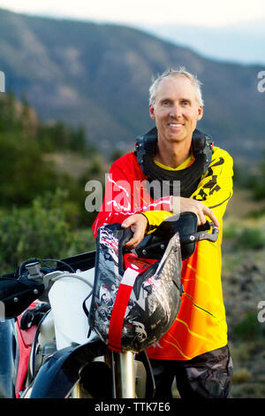 Ritratto di uomo con casco mentre in piedi da dirt bike Foto Stock