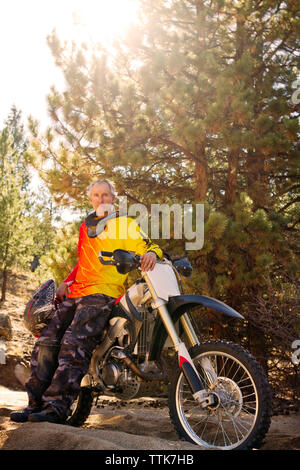 Ritratto di uomo in piedi da dirt bike contro alberi Foto Stock