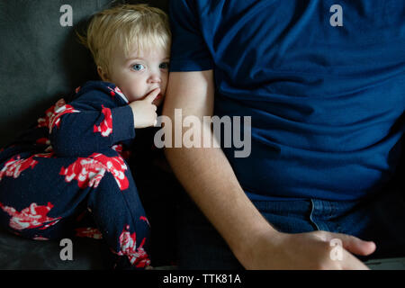 Il Toddler boy mano fa il gesto di essere tranquillo mentre è seduto accanto al padre sul lettino Foto Stock