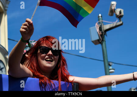 Donna con testa rossa che sventola bandiera arcobaleno alla sfilata Helsinki Pride 2016 a Helsinki, Finlandia Foto Stock