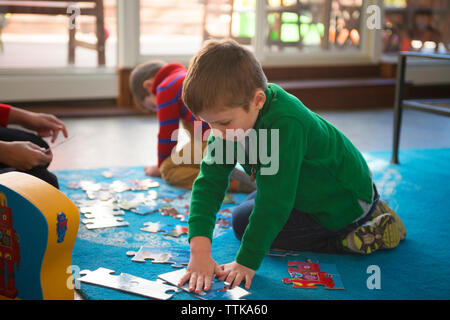 Fratello giocare con puzzle su un tappeto a casa Foto Stock