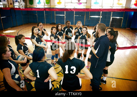 Angolo di Alta Vista del coach per spiegare le ragazze adolescenti in campo da pallavolo Foto Stock