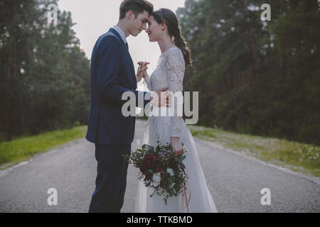 Vista laterale del matrimonio coppia danzante sulla strada in mezzo di alberi Foto Stock