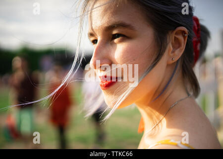 Close-up di sorridere premurosa donna che guarda lontano rimanendo in posizione di parcheggio Foto Stock