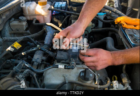 Immagine ritagliata di mani riparazione motore del veicolo Foto Stock