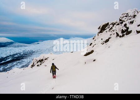 Escursionista sulla coperta di neve montagna contro il cielo nuvoloso Foto Stock