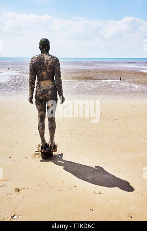 Uno dei Anthony Gormley statue in Crosby spiaggia che si trova più vicino alla linea di galleggiamento Foto Stock