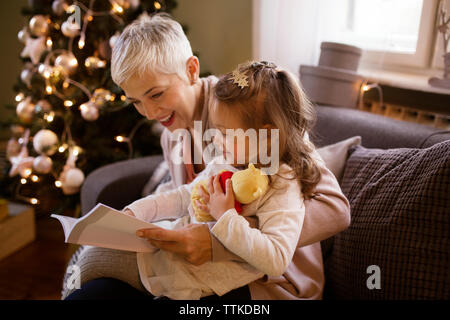 Nonna e nipote lettura Prenota comodamente seduti sul divano di casa Foto Stock