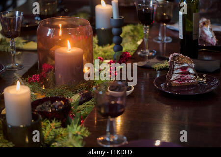 Dessert e bicchieri di vino sul tavolo da pranzo illuminato durante il natale Foto Stock