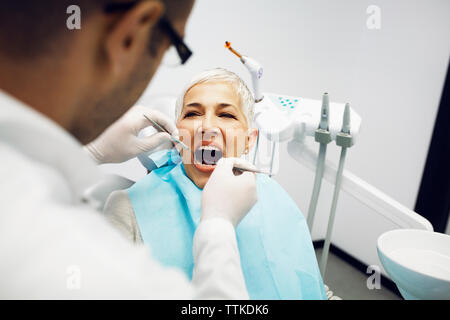 Dentista maschio esaminando denti del paziente presso la clinica Foto Stock