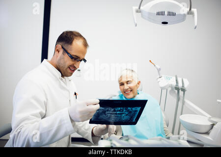 Dentista spiegando x-ray a sorridere paziente presso la clinica Foto Stock