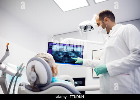 Dentista spiegando raggi x al paziente di sesso femminile in cliniche Foto Stock