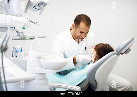 Dentista sorridente ragazza di esaminare i denti in cliniche Foto Stock